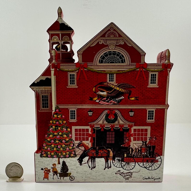 May include: A red wooden Christmas ornament depicting a firehouse with a Christmas tree, a horse-drawn carriage, and the text "Protection".