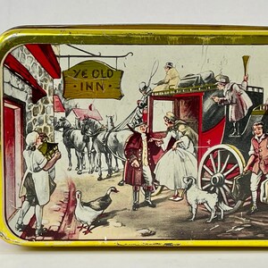 May include: A vintage tin box with a colorful illustration of a horse-drawn carriage arriving at a quaint inn. The sign above the inn reads "Ye Olde Inn".