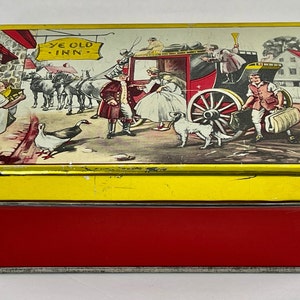 May include: A vintage tin box with a red base and a yellow lid. The lid features a colorful illustration of a horse-drawn carriage with passengers, a sign that reads "Ye Old Inn", and a group of people standing outside a building.
