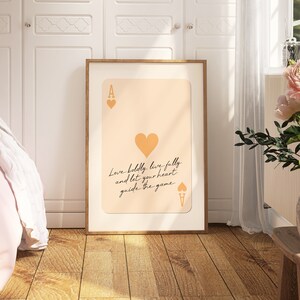 May include: A printable poster featuring a stylized illustration of an ace of hearts playing card with the text "Love boldly, live fully and let your heart guide the game." The background is a light peach color.