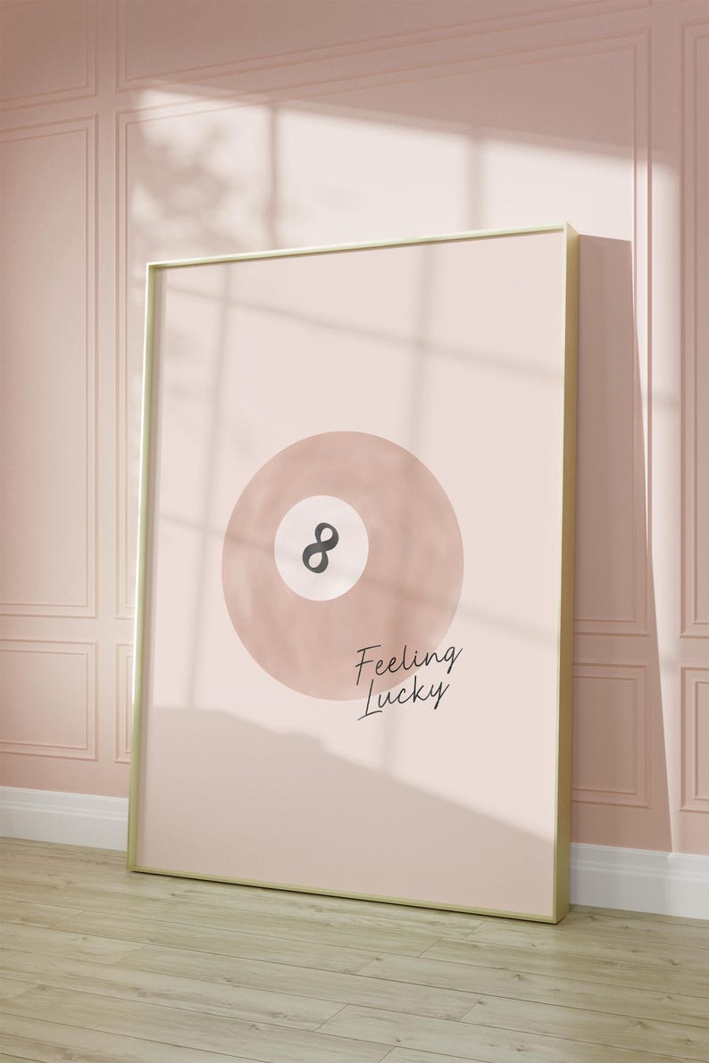 Pode incluir: Uma ilustra&ccedil;&atilde;o em aquarela rosa e branca de uma bola de bilhar com o n&uacute;mero oito nela. O texto "Feeling Lucky" est&aacute; escrito abaixo da bola.