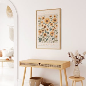May include: A framed print of a botanical illustration of sunflowers with the text "FLOWER MARKET! LONDON" and the words "GALERIE D'ART MODERNE" and "COLLECTION BOTANIQUE" at the bottom.