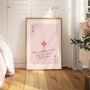 May include: A pink and white printable wall art design featuring an ace of diamonds playing card with the quote "A diamond doesn't ask if it can shine. It just does."