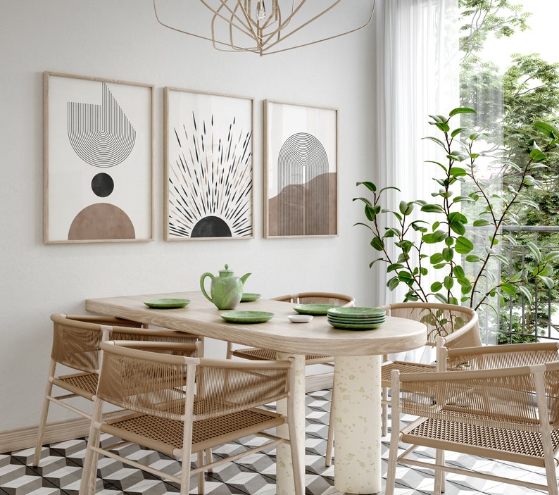 Puede incluir: Una mesa de comedor con seis sillas, una tetera y cuatro platos. La mesa es de madera y tiene un acabado marr&oacute;n claro. Las sillas son de mimbre tejido y tienen un acabado natural. Las paredes son blancas y presentan tres estampados geom&eacute;tricos abstractos en negro, blanco y marr&oacute;n. Una planta con hojas verdes est&aacute; en la esquina de la habitaci&oacute;n.