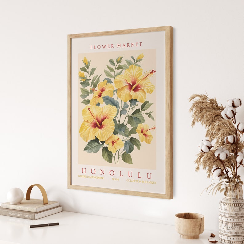 May include: A vintage botanical illustration of yellow hibiscus flowers with green leaves. The print is framed in wood and has the text "FLOWER MARKET HONOLULU GALERIE D'ART MODERNE NO. 14 COLLECTION BOTANIQUE" at the top and bottom.