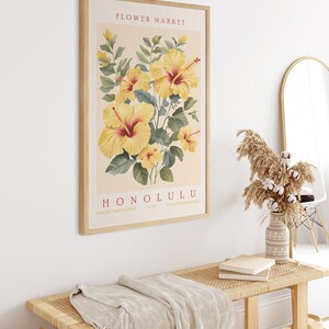 May include: A framed botanical print featuring yellow hibiscus flowers with red centers. The print is titled "FLOWER MARKET HONOLULU" with the text "GALERIE D'ART MODERNE" and "COLLECTION FROM HAWAII" at the bottom.