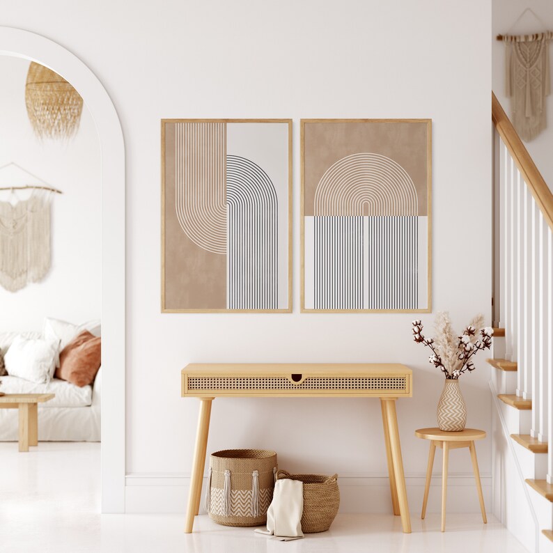 Peut inclure: Deux impressions d'art abstraites encadr&eacute;es avec des motifs g&eacute;om&eacute;triques beiges, noirs et blancs sont accroch&eacute;es au-dessus d'une console en bois clair. Des paniers en osier et un petit tabouret en bois avec un vase de fleurs s&eacute;ch&eacute;es compl&egrave;tent le d&eacute;cor de l'entr&eacute;e.