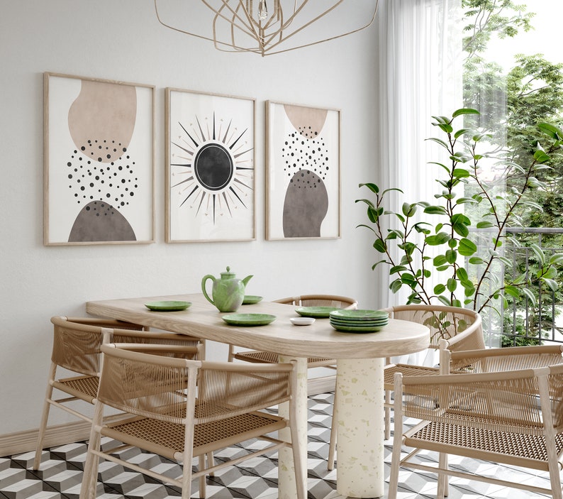 Puede incluir: Un comedor con una mesa de madera ovalada y seis sillas. La mesa es de madera clara y las sillas son de mimbre tejido de color marr&oacute;n natural. Hay tres impresiones de arte abstracto en la pared detr&aacute;s de la mesa. Las impresiones son en tonos de marr&oacute;n, beige y negro. Una tetera verde y cuatro platos verdes est&aacute;n sobre la mesa. La habitaci&oacute;n tiene una pared blanca y una ventana grande con cortinas blancas.
