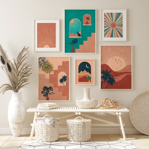 Peut inclure: Ensemble d'impressions d'art encadr&eacute;es sur les th&egrave;mes du d&eacute;sert et du coucher de soleil. Les impressions pr&eacute;sentent des palettes de couleurs chaudes avec des images de soleils, de palmiers, d'escaliers et d'un chat. L'art est expos&eacute; au-dessus d'un banc blanc avec des paniers tress&eacute;s et un vase d&eacute;coratif.
