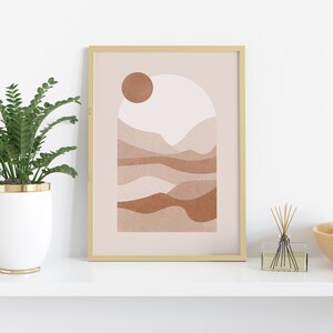 May include: A framed abstract print with a minimalist design featuring a sun, mountains, and a light pink and brown color scheme.