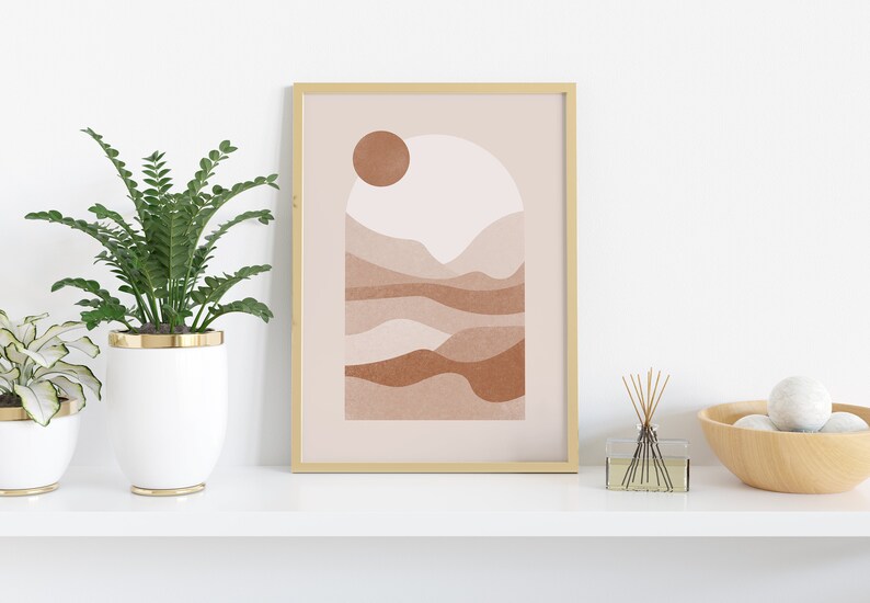 May include: A framed abstract print with a minimalist design featuring a sun, mountains, and a light pink and brown color scheme.