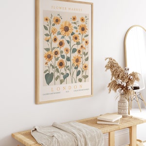 May include: A framed print with a botanical illustration of sunflowers in shades of yellow and green. The print has the text "FLOWER MARKET LONDON NO.3 COLLECTION BOTANIQUE GALERIE D'ART MODERNE" at the bottom.