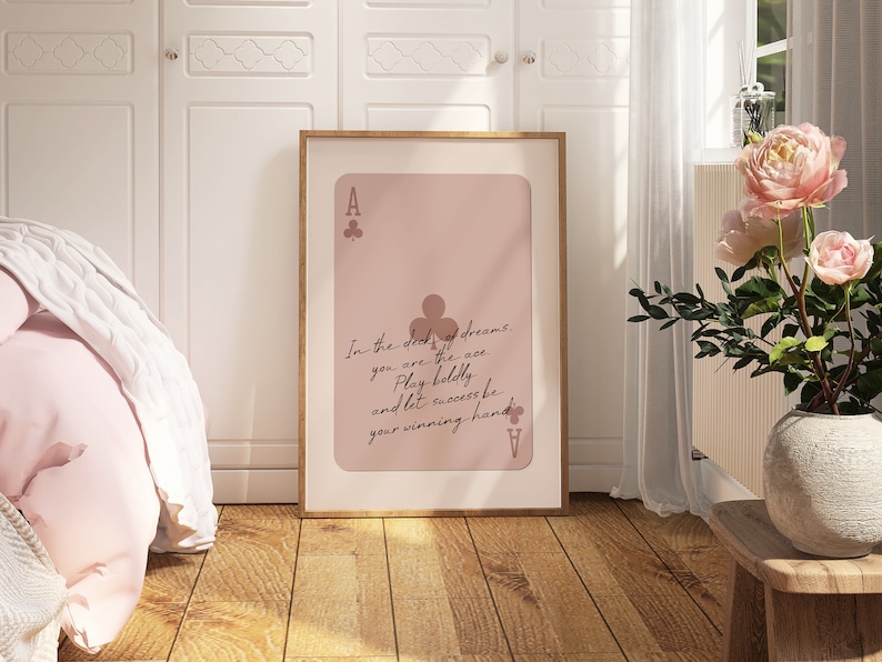 May include: A pink and brown poster with a playing card design. The card is an ace of clubs and has the text "In the deck of dreams, you are the ace. Play boldly and let success be your winning hand."