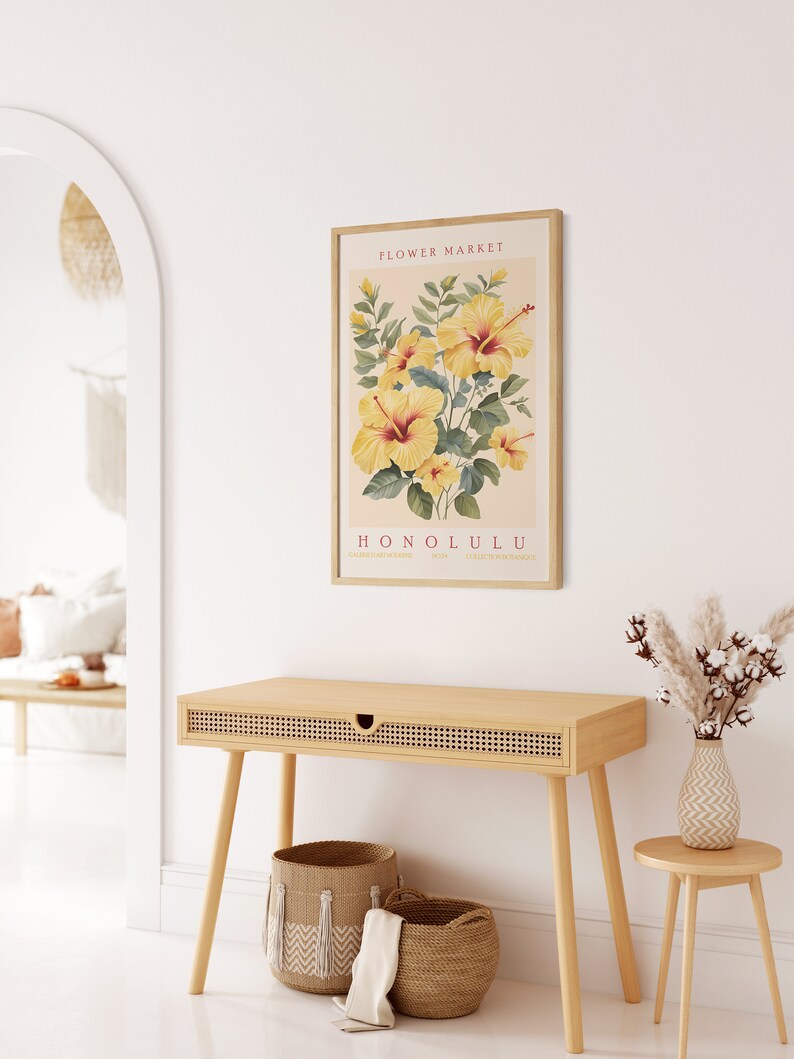May include: A framed print with a vintage aesthetic featuring a botanical illustration of yellow hibiscus flowers with green leaves. The print has the text "FLOWER MARKET HONOLULU" in red and black lettering.
