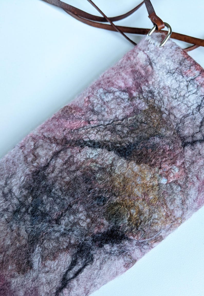 May include: A small, pink, grey, and brown felted bag with a brown leather strap and silver hardware.