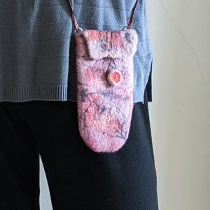 May include: A pink and purple felted wool crossbody bag with a brown leather strap and a small pink pom-pom accent.