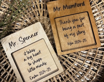 May include: Two wooden plaques with engraved text. One reads "Mr. Spenner" with the quote "it takes a big heart to shape little minds" and "Easton 2024-25." The other says "Mr. Mumford" with "Thank you for being a part of my story. Kyla 2024-25."