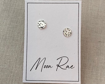 May include: A pair of silver hammered circle stud earrings on a white card with the text "Moon Rae" in black script.