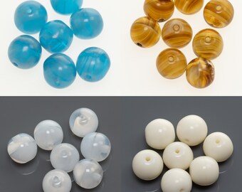 Könnte beinhalten: Sortiment runder, bunter Glasperlen. Die Perlen sind in drei Farben: blau, braun und weiß. Die Perlen sind alle etwa gleich groß und haben eine glatte, polierte Oberfläche.
