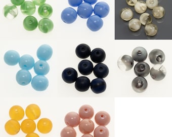 Könnte beinhalten: Sortiment an Glasperlen in verschiedenen Farben, darunter Grün, Blau, Hellblau, Dunkelblau, Grau und Rosa. Die Perlen sind rund und haben eine glatte, glänzende Oberfläche.
