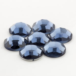 Op de afbeelding: Zeven donkerblauwe, gefacetteerde, ronde strasssteentjes.