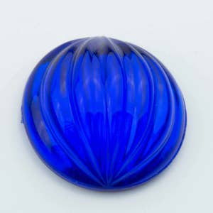 May include: A blue glass cabochon with a ribbed design. The cabochon is round and has a smooth, polished surface.
