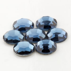 Op de afbeelding: Zeven donkerblauwe, gefacetteerde, ronde strasssteentjes.