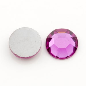 Puede incluir: Un solo strass redondo de color rosa con un dorso plano. El strass tiene un dise&ntilde;o facetado y un acabado brillante.