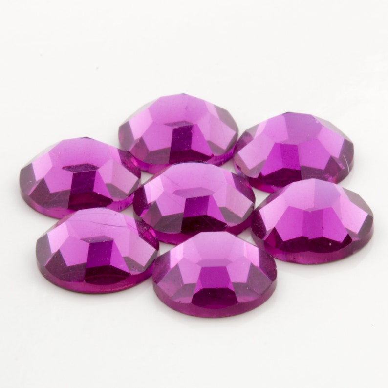 Puede incluir: Siete piedras de cristal redondas, facetadas, de color morado. Las piedras de cristal est&aacute;n dispuestas en c&iacute;rculo con las puntas hacia afuera.