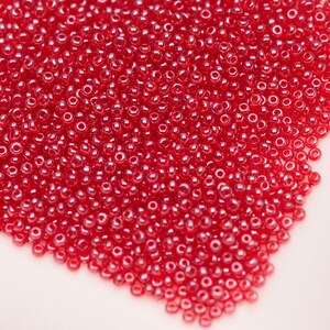 May include: A large pile of small, red, round glass beads.