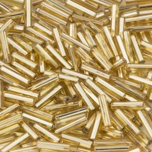 May include: A large pile of gold glass beads in a tube shape. The beads are translucent and have a shiny finish.