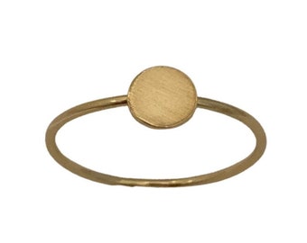 May include: A simple gold ring with a round, flat disc in the center.
