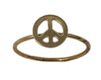 May include: A gold peace sign ring. The ring is thin and delicate, with a simple peace sign design.