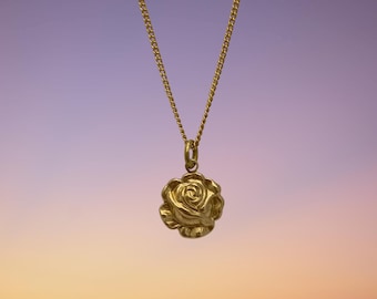 May include: A gold chain necklace with a rose-shaped pendant. The pendant is detailed and textured, with a realistic rose design.