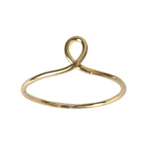May include: A simple gold ring with a unique, twisted design. The ring is made of a thin wire and has a delicate, minimalist look.