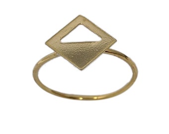 May include: A gold ring with a geometric diamond-shaped design. The ring has a textured finish and a cut-out triangle shape in the center.