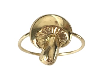 May include: A gold-colored ring with a mushroom design. The mushroom is detailed with a textured cap and a smooth stem.