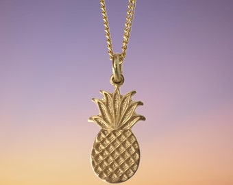 May include: A gold pineapple pendant necklace. The pineapple is detailed with a textured surface and a leafy top.