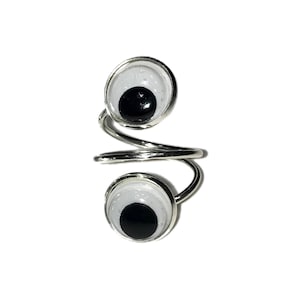 May include: A silver ring with two white and black googly eyes. The ring is twisted and has a spiral design.