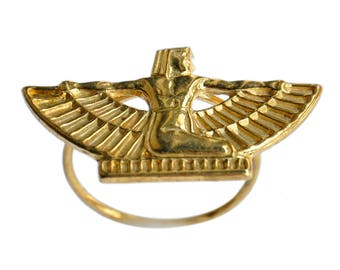 May include: A gold-colored metal ring with a winged figure design. The figure is sitting with its wings spread out. The ring is a decorative piece.