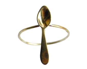May include: A gold spoon ring with a thin band and a small spoon charm. The spoon is oval shaped with a rounded end.