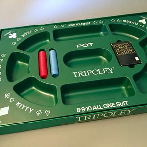 May include: A green plastic Tripoley game board tray with molded compartments for tokens and cards. The board features white text including POT, KITTY, 8-9-10 ALL ONE SUIT, and TRIPOLEY, along with card suit symbols. One red and one blue stack of chips are included.