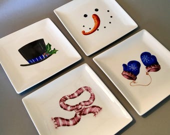 Unique set of four festive 6.25” appetizer or dessert plates featuring a top hat, snowman face, scarf and mittens