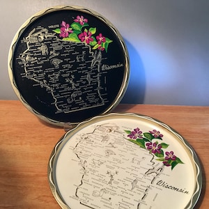 May include: Two vintage round trays with a map of Wisconsin. One tray is black with gold trim, the other is cream-colored. Both feature a floral design of purple violets and green leaves. The trays have a scalloped edge.