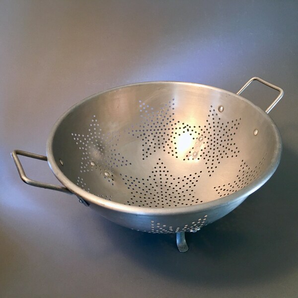 Large vintage aluminum colander strainer featuring a star pattern with feet and handles