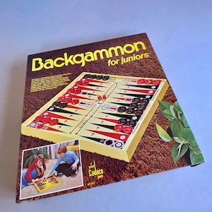 May include: A vintage "Backgammon for Juniors" board game. The yellow game board features red and black checkers, dice, and a playing surface. The box has a brown background with the game title in yellow. A smaller image shows children playing.