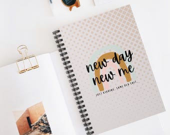 Puede incluir: Cuaderno de espiral con una cubierta con un diseño de arcoíris y el texto "new day new me". El cuaderno tiene un fondo con patrón de puntos y la frase "JUST KIDDING, SAME OLD SHIT."