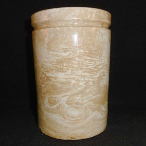 May include: A white ceramic cylindrical vase with a marbled pattern. The vase has a smooth, rounded top and bottom.