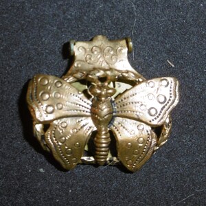 May include: Gold-toned metal butterfly charm with intricate details. The butterfly has a detailed body and wings with a decorative border.