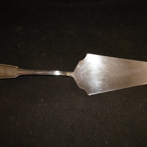 May include: A silver cake server with a decorative shell design on the handle.